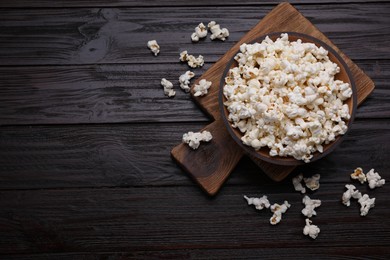 Photo of Tasty popcorn on black wooden table, flat lay. Space for text