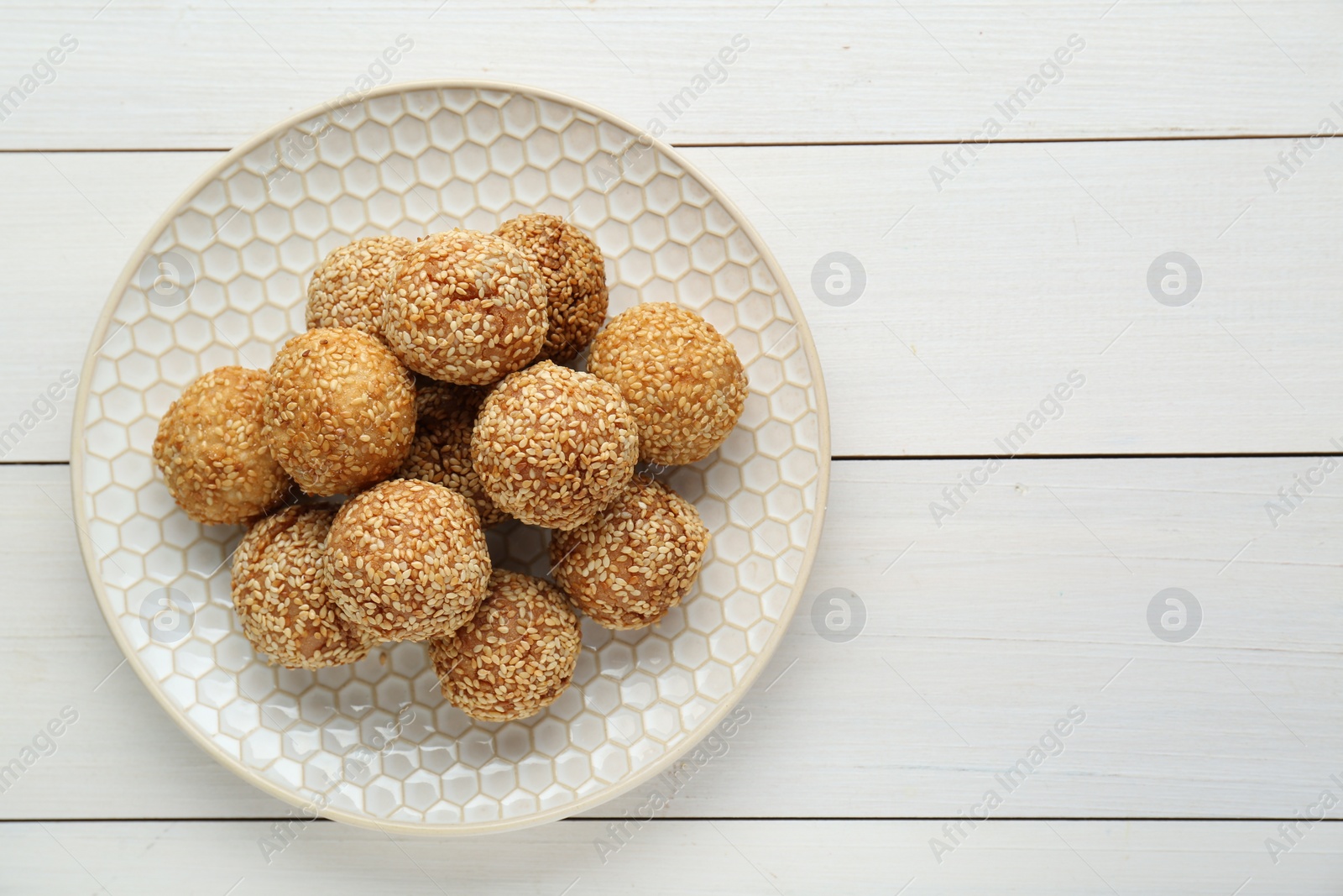 Photo of Delicious sesame balls on white wooden table, top view. Space for text