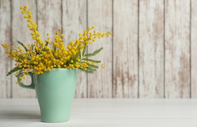 Bouquet of beautiful mimosa flowers on white wooden table. Space for text