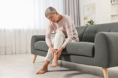 Arthritis symptoms. Woman suffering from pain in leg at home