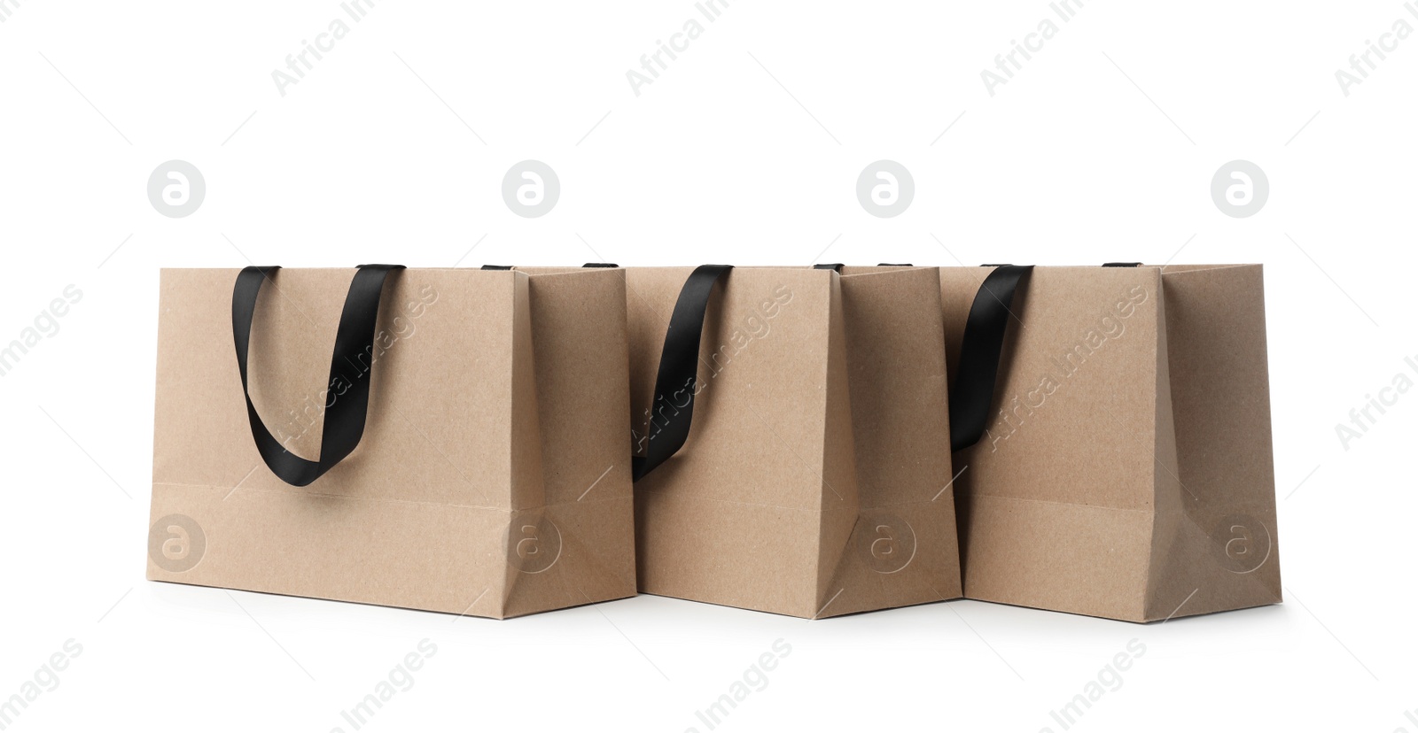 Photo of Paper shopping bags with ribbon handles on white background. Mockup for design