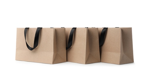 Photo of Paper shopping bags with ribbon handles on white background. Mockup for design