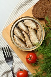 Canned sprats, dill, tomatoes, bread and fork on light table, flat lay