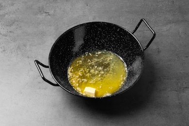 Photo of Frying pan with melting butter on grey table