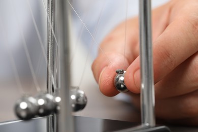 Photo of Man playing with Newton's cradle, closeup. Physics law of energy conservation