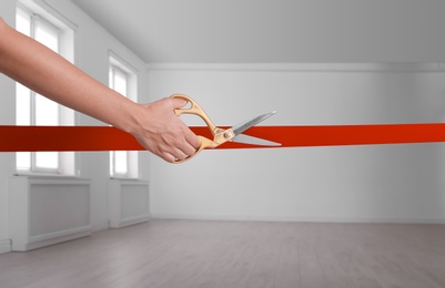 Photo of Woman cutting red ribbon on blurred background. Festive ceremony