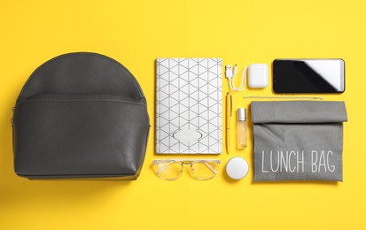 Photo of Stylish urban backpack and different items on yellow background, flat lay