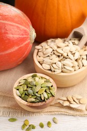 Photo of Bowls with seeds and fresh pumpkins on light wooden table