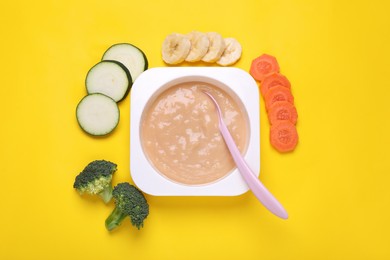 Container with healthy baby food and ingredients on yellow background, flat lay