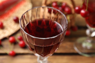 Photo of Delicious cherry wine in glass on wooden table, closeup