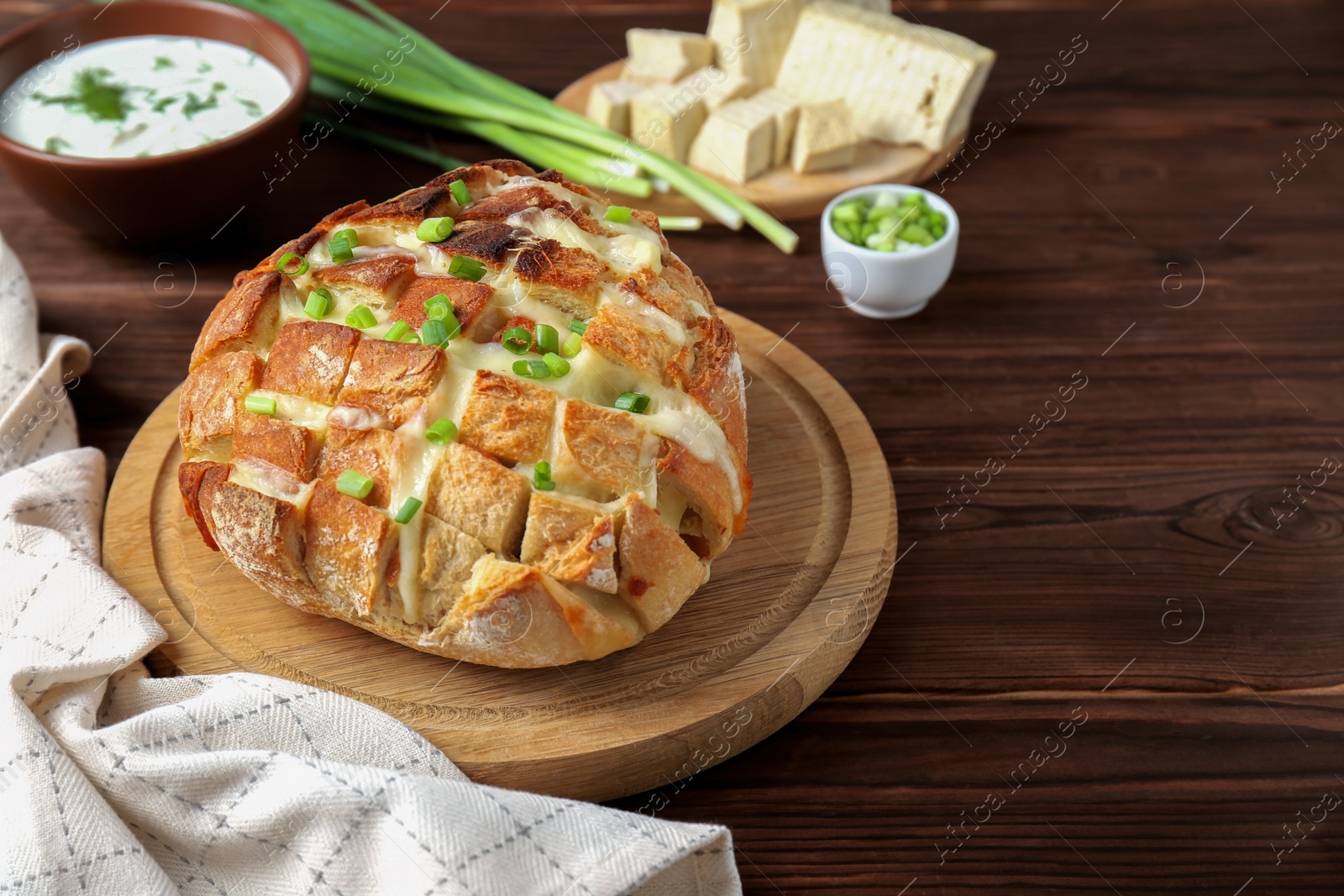Photo of Freshly baked bread with tofu cheese and green onions on wooden table. Space for text
