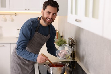 Photo of Man cooking tomato soup on cooktop in kitchen