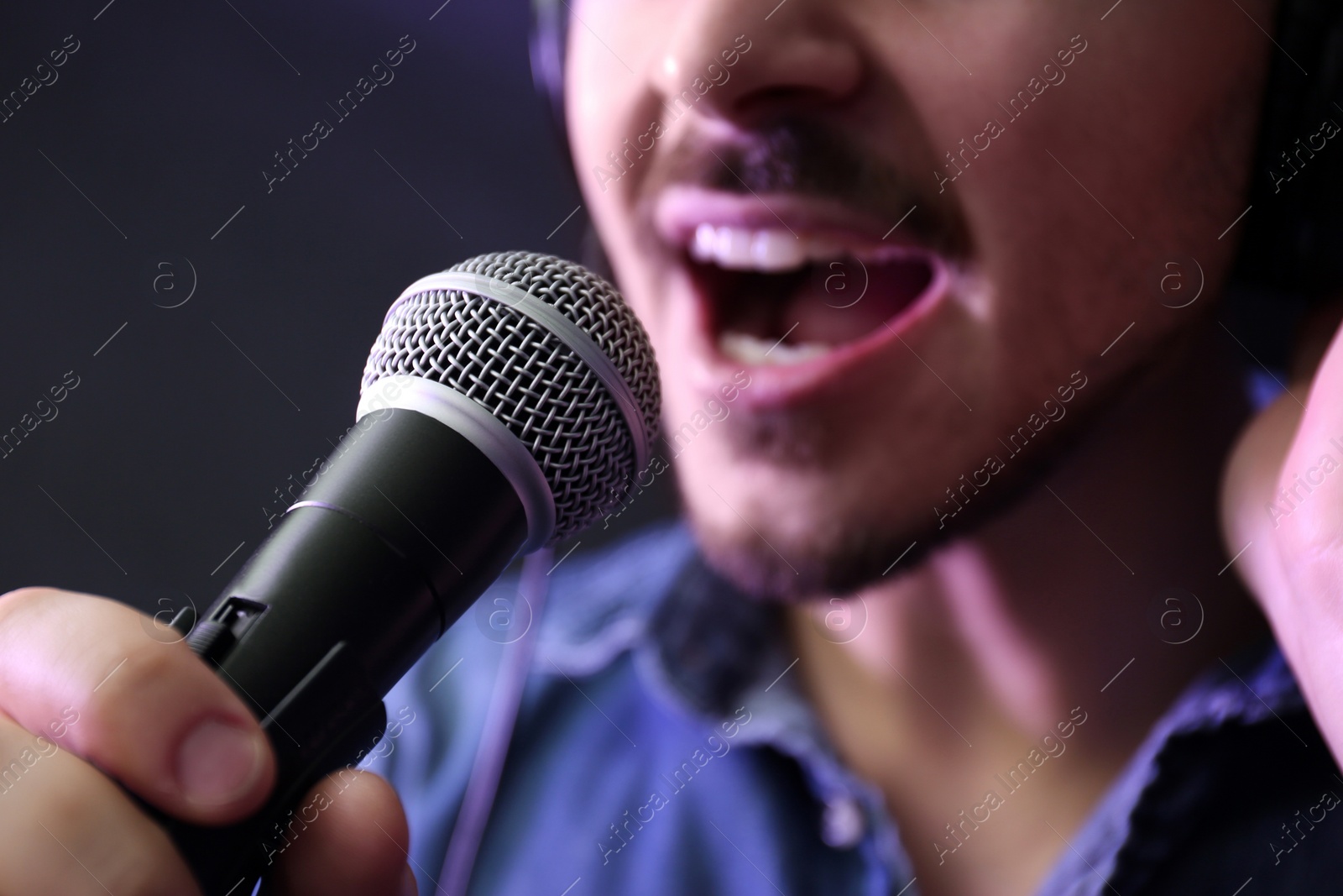 Photo of Young singer with microphone recording song in studio, closeup