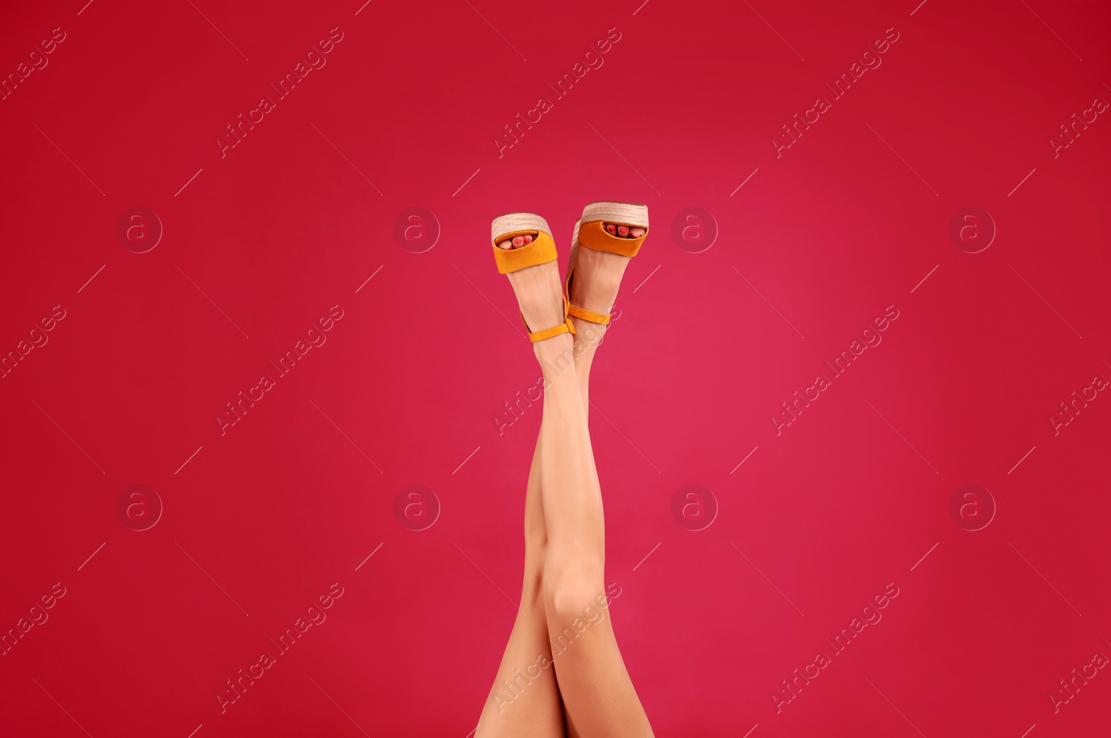 Photo of Woman in stylish shoes on crimson background