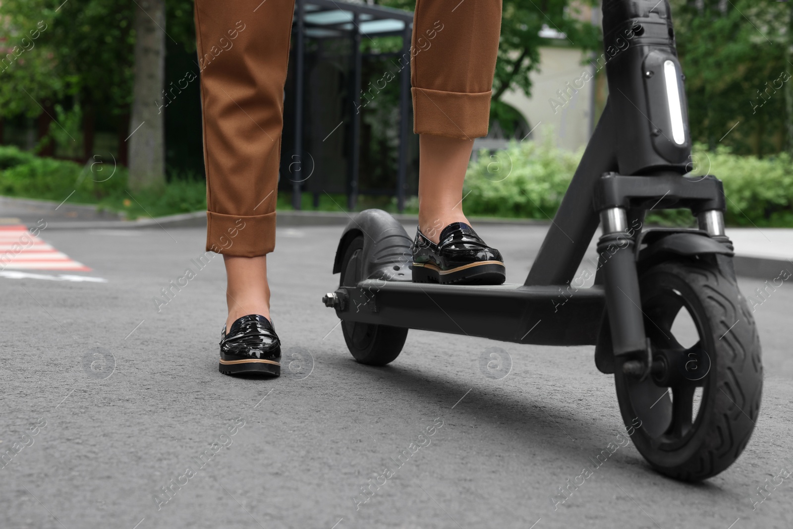 Photo of Businesswoman with modern electric kick scooter on city street, closeup