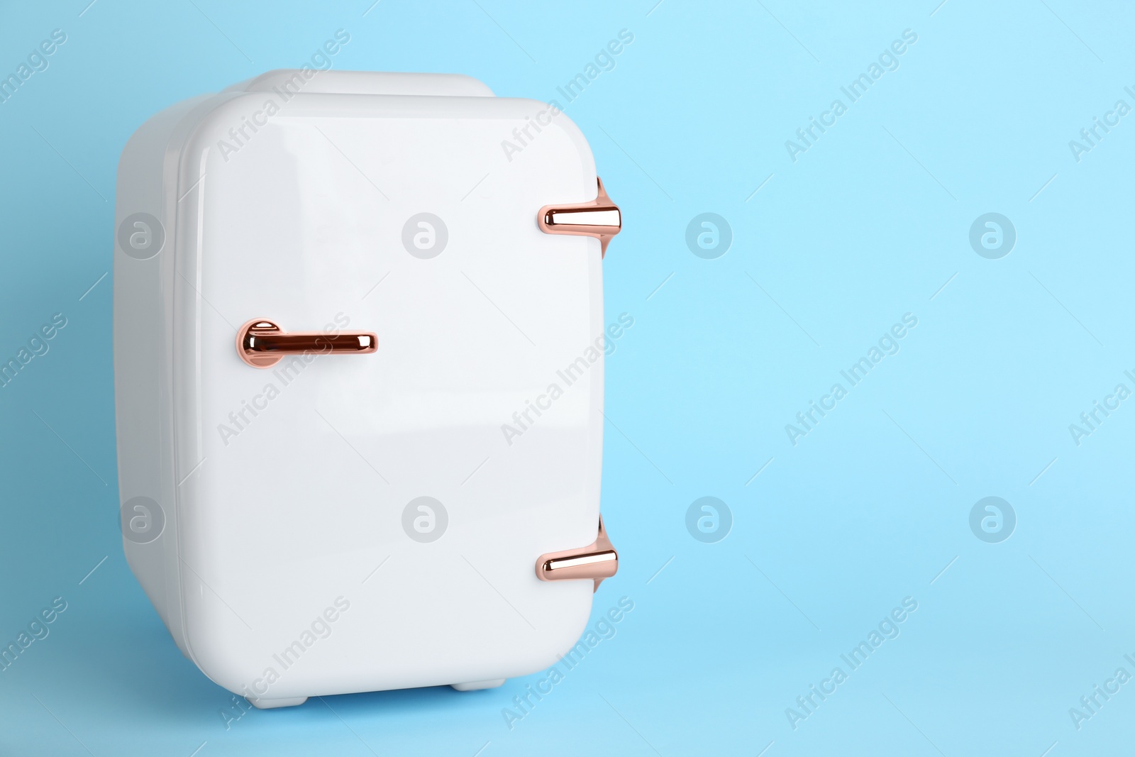 Photo of White cosmetics refrigerator on light blue background, space for text