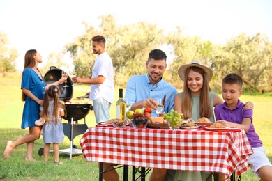 Photo of Happy families with little children having picnic in park