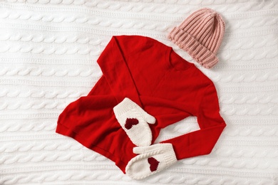 Red cashmere sweater, hat and mittens on knitted plaid, top view