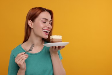 Photo of Young woman eating piece of tasty cake on orange background, space for text
