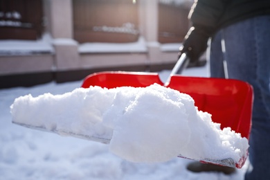 Photo of Person shoveling snow outdoors on winter day, closeup