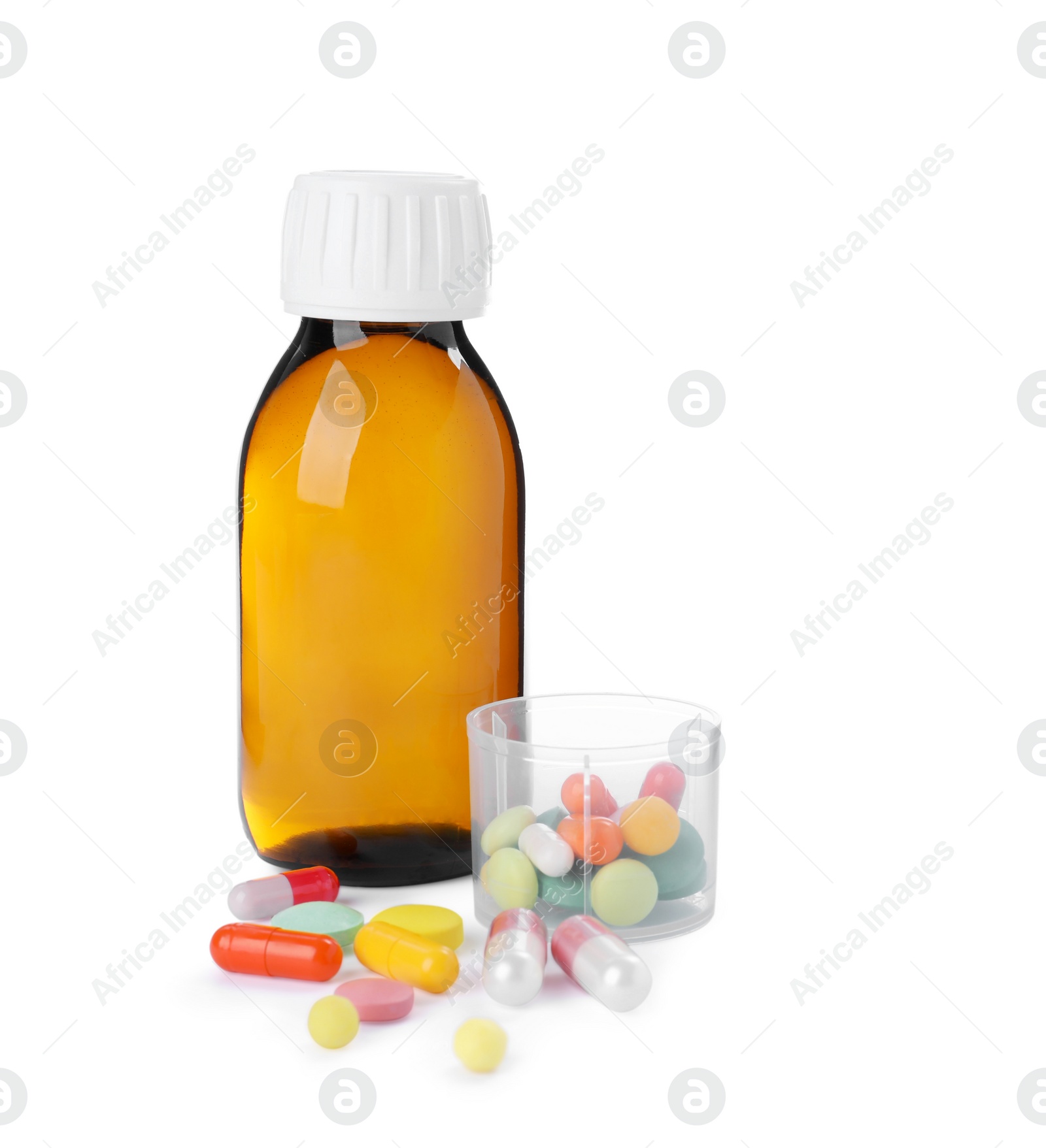 Photo of Bottle of syrup, measuring cup with pills on white background. Cough and cold medicine