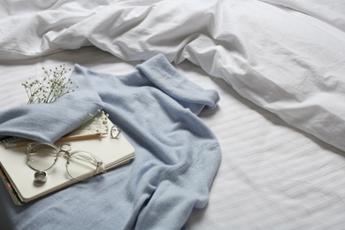 Composition with soft cashmere sweater on bed at home, space for text