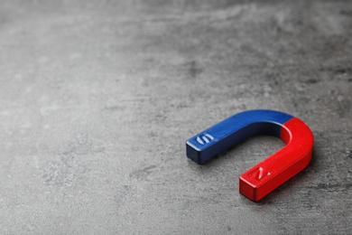 Red and blue horseshoe magnet on grey background. Space for text