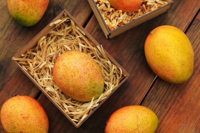 Photo of Delicious ripe juicy mangos on wooden table, flat lay