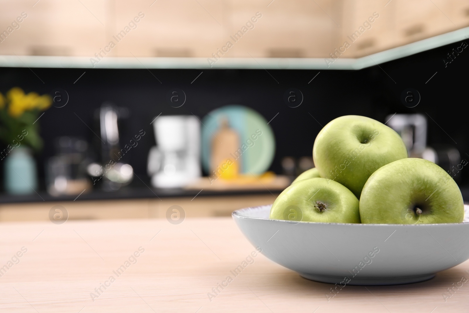 Photo of Fruit bowl with apples on table in kitchen, selective focus