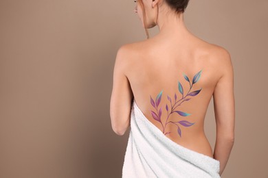 Image of Young woman with beautiful floral tattoo on beige background, back view. Space for text