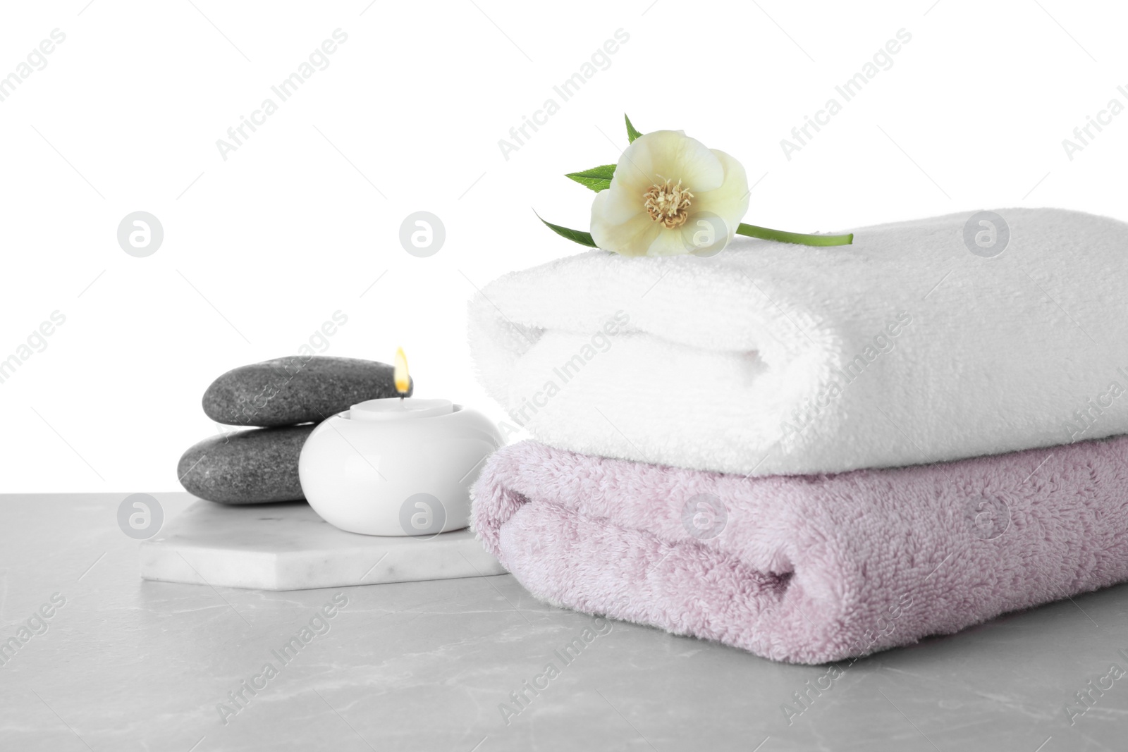 Photo of Towels, spa stones and flower on marble table against white background