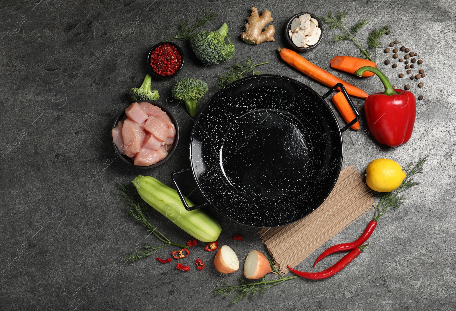 Photo of Empty iron wok surrounded by raw ingredients on grey table, flat lay