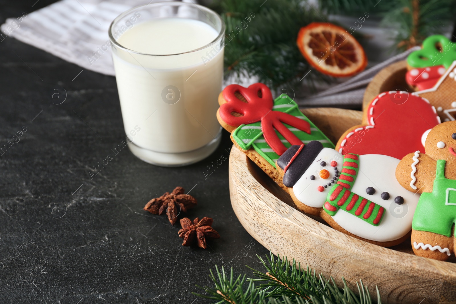 Photo of Tasty Christmas cookies near glass of milk on black table