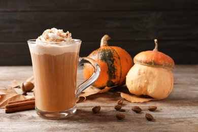 Photo of Glass cup with tasty pumpkin spice latte on wooden table
