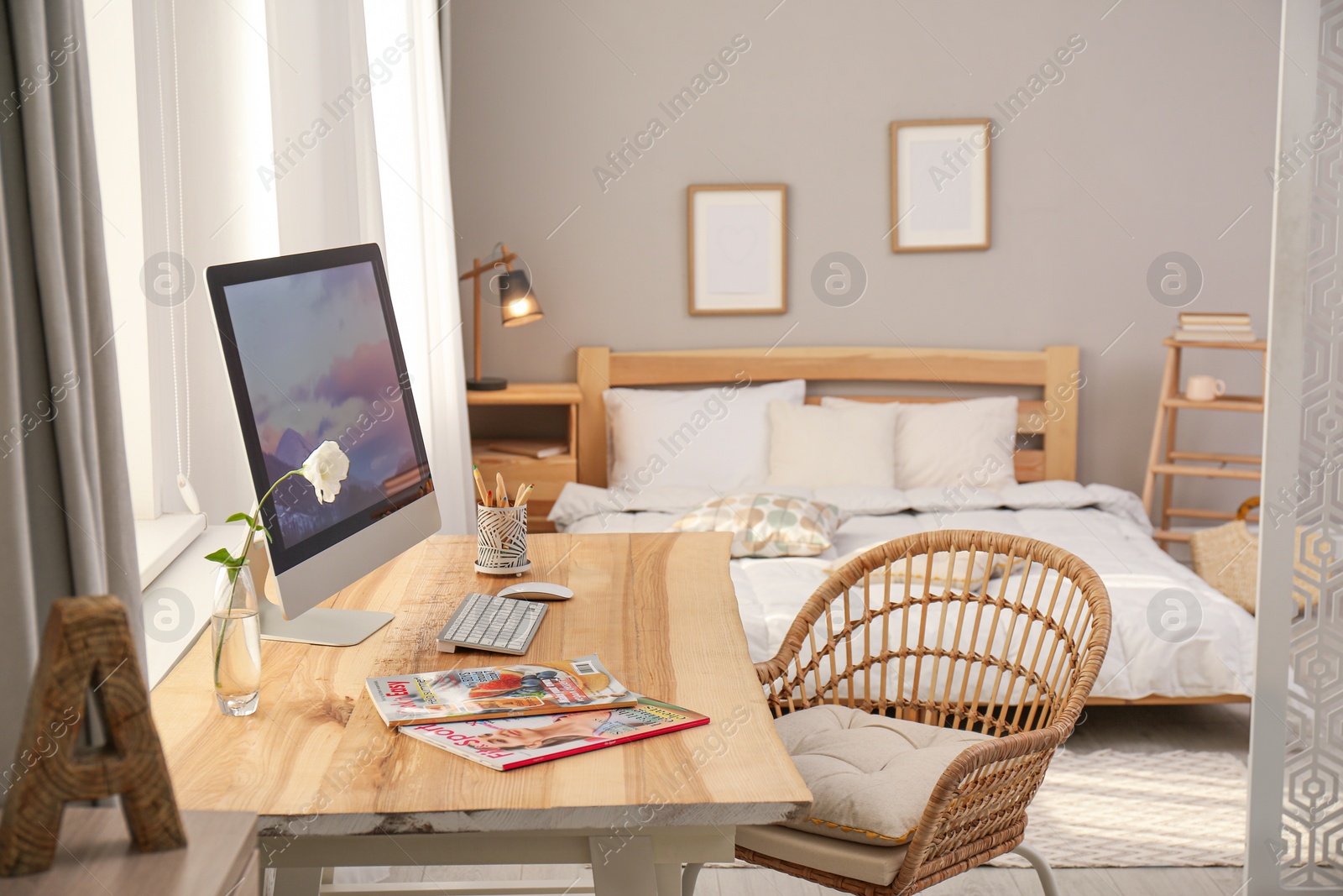 Photo of Comfortable workplace with modern computer near window in bedroom. Interior design