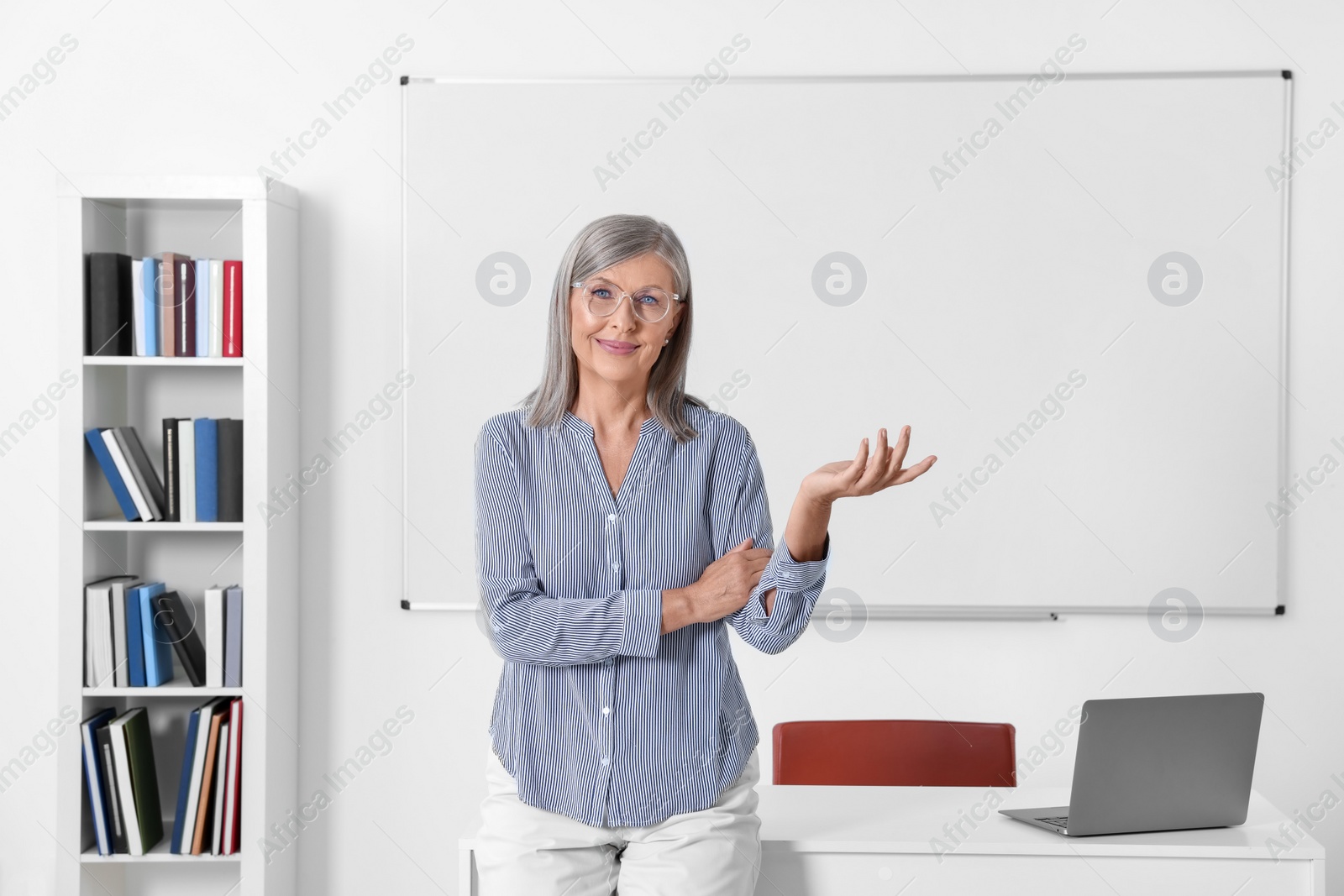 Photo of Portrait of smiling professor near whiteboard in classroom