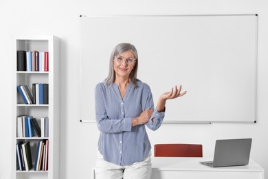 Photo of Portrait of smiling professor near whiteboard in classroom