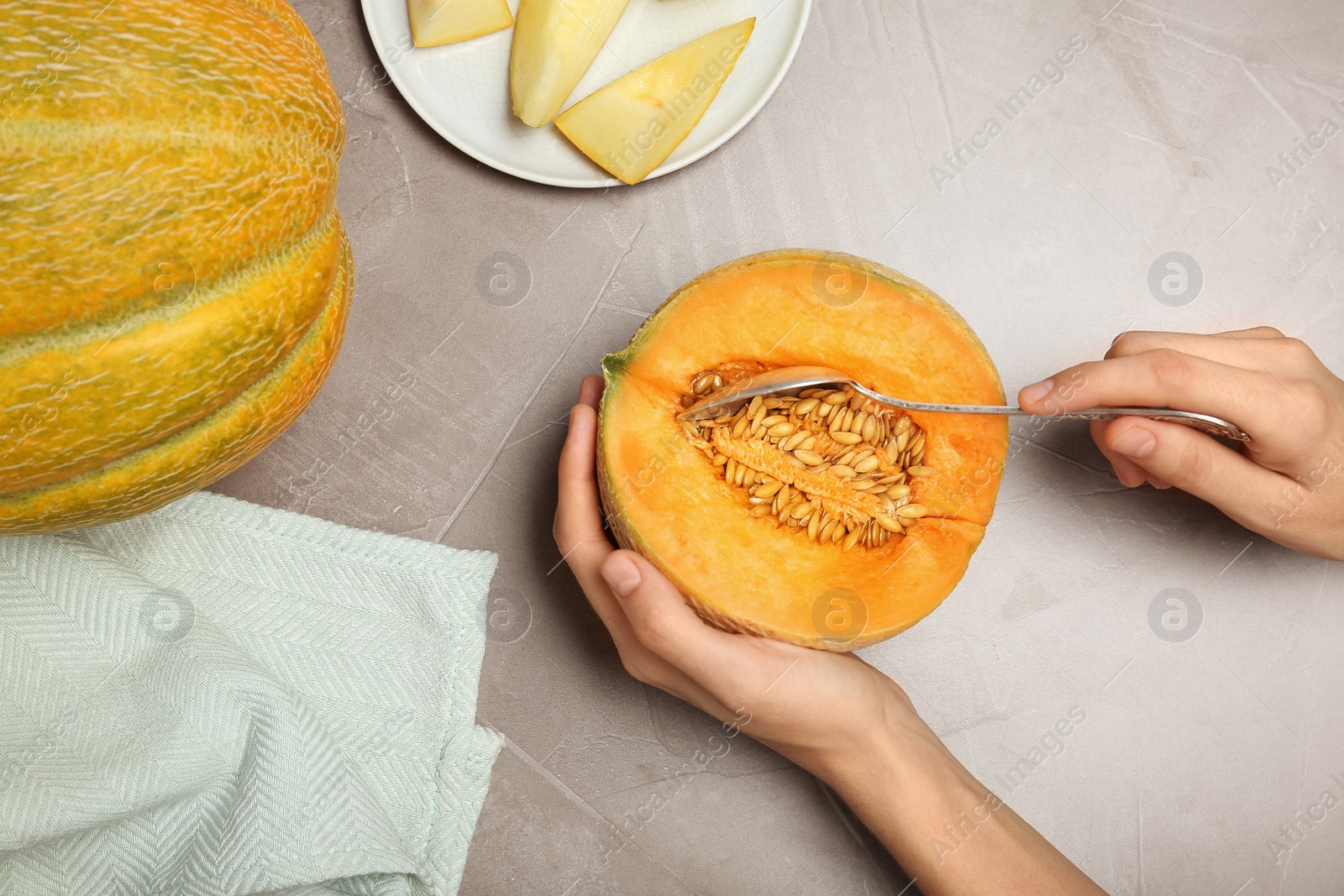 Photo of Woman holding ripe tasty melon at table, top view