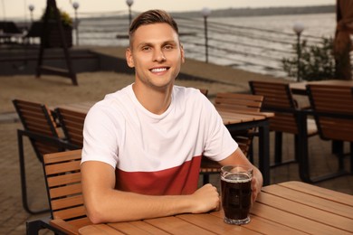 Photo of Man with glass of dark beer in outdoor cafe