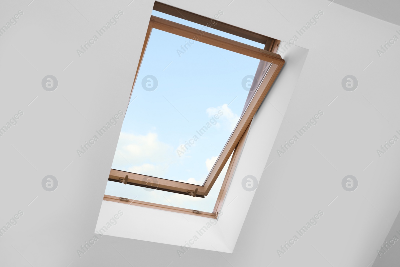 Photo of Skylight roof window and lamps on slanted ceiling in attic room, low angle view