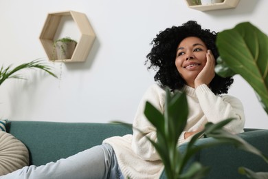 Photo of Relaxing atmosphere. Woman on sofa near beautiful houseplants at home