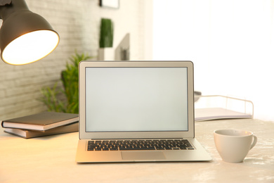 Photo of Modern laptop and cup of coffee on white table indoors. Space for design