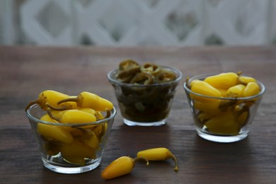 Photo of Pickled green and yellow jalapeno peppers on wooden table