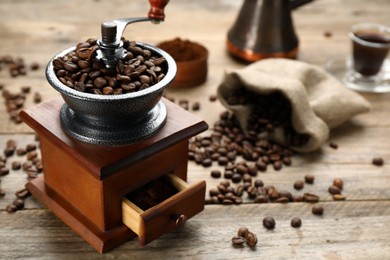 Photo of Vintage manual coffee grinder and beans on wooden table. Space for text
