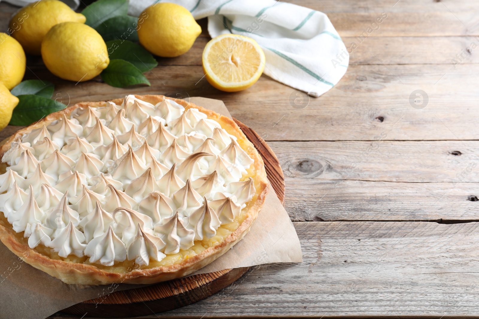 Photo of Delicious lemon meringue pie on wooden table. Space for text