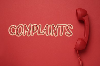 Corded telephone handset and word complaints on red background, top view