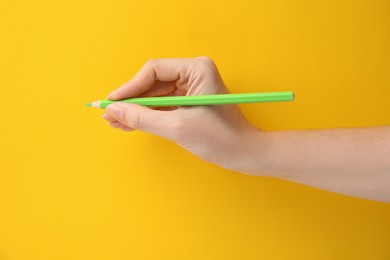 Photo of Woman with green pencil on yellow background, closeup. Space for text