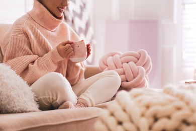 Woman with cup of drink relaxing at home, closeup. Cozy atmosphere