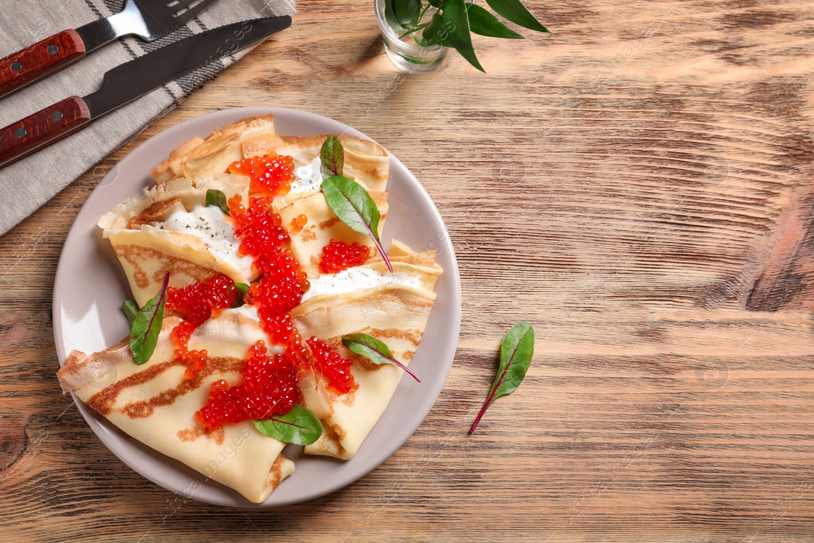 Photo of Thin pancakes with red caviar on plate, top view