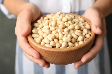 Photo of Woman holding bowl with shelled peanuts, closeup
